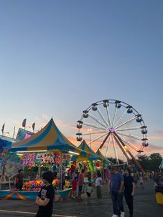 people walking around an amusement park at sunset