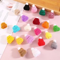 small knitted hearts are displayed on a pink surface next to a piece of paper