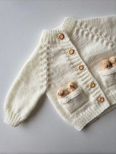 a knitted sweater with two teddy bears on the front and back buttons, sitting on a white surface