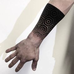 a man's hand with a black and white tattoo on it, next to a wall