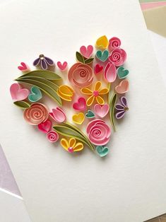 paper flowers are arranged in the shape of a heart on a piece of white paper