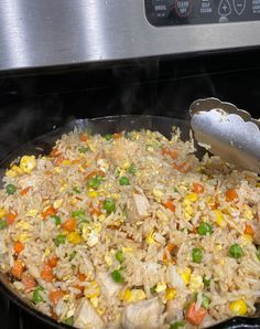 a pan filled with rice and vegetables cooking on top of an electric stove burner