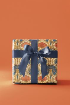 a wrapped gift box with a blue ribbon and bow on an orange background is shown