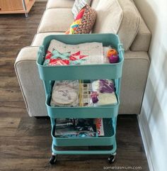 a blue cart sitting on top of a hard wood floor next to a white couch