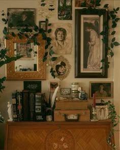 there is a dresser with many pictures on the wall and plants growing out of it