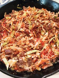 a skillet filled with meat and vegetables on top of a stove