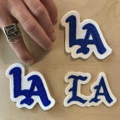 someone's hand next to three letters that spell out the word la