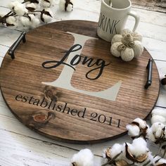 a round wooden sign that says long established 2011 with cotton floss next to it