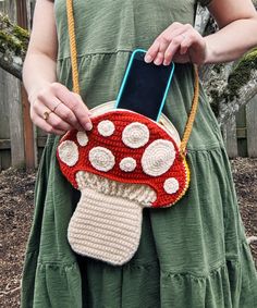 a woman in a green dress is holding a cell phone and mushroom purse with holes on it