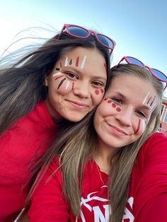 two girls with face paint on their faces and one girl has her arm around the other