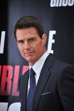 a man in a suit and tie posing for the camera at a red carpet event