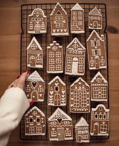 a person is decorating gingerbread houses with icing on a wire cooling rack