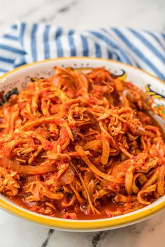 a bowl filled with shredded red onions on top of a marble countertop next to a blue and white striped towel