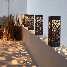 four decorative lanterns are lit up on a wall