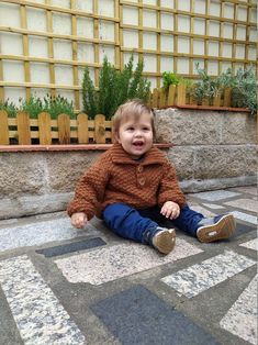 a little boy sitting on the ground smiling