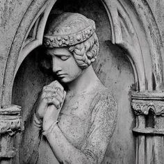 a black and white photo of a statue with her hands clasped in front of her face