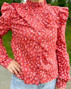 This Leopard Poplin Ruffle Top in tomato print is a stylish addition to any wardrobe. Made with soft and breathable poplin fabric, its ruffled design adds a feminine touch to any outfit. Perfect for those who want to make a statement, this versatile top can be dressed up or down for any occasion. Printed Cotton Blouse With Ruffle Sleeves, Patterned Fitted Tops With Ruffles, Fitted Patterned Tops With Ruffles, Fitted Patterned Top With Ruffles, Patterned Cotton Tops With Ruffles, Trendy Blouse With Ruffled Collar And Hem, Trendy Blouse With Ruffle Hem And Ruffled Collar, Casual Patterned Blouse With Ruffles, Chic Red Top With Ruffle Hem