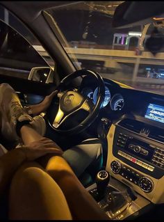 a person sitting in the driver's seat of a car with their feet on the steering wheel