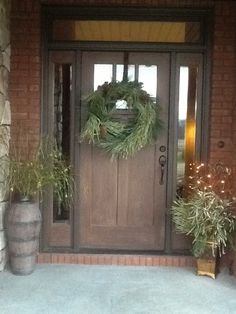 the front door is decorated with wreaths and potted plants