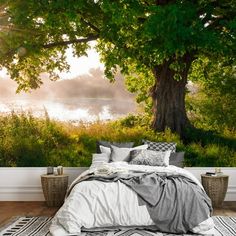 a bed sitting under a tree next to a wall