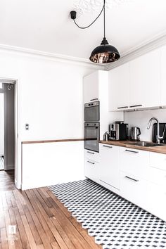 a kitchen with white cabinets and black and white checkered flooring on the tile