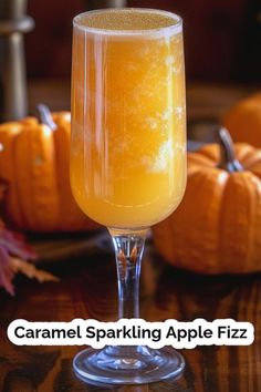 a glass filled with liquid sitting on top of a wooden table next to pumpkins