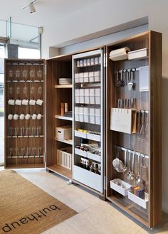 an open bookcase with lots of books and glasses on it in a room next to a window