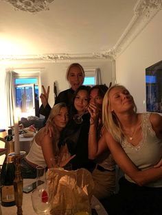 a group of women standing next to each other in front of a table filled with food and drinks