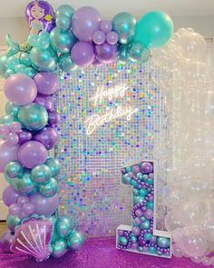 a purple and blue balloon arch with mermaid balloons on it's sides, along with an under the sea theme