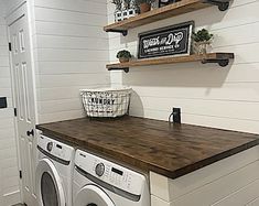 a washer and dryer in a small room with shelves on the wall above them