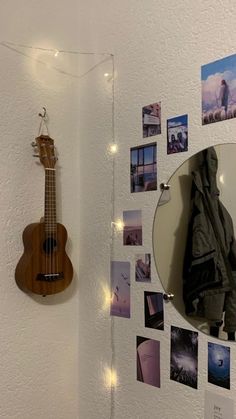 a guitar hanging on the wall next to a mirror with pictures and lights around it