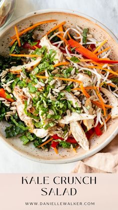 a salad with carrots, lettuce and chicken in a white bowl on a marble surface