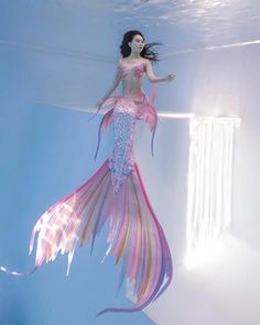 a woman dressed as a mermaid floating in the water