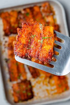 a fork with some food on it in front of a pan filled with other foods