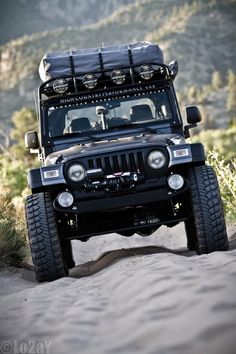 a black jeep driving down a sandy road