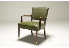 a green leather chair sitting on top of a white floor next to a wooden frame