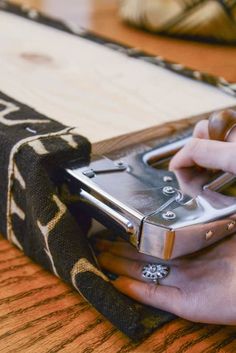 a person is holding a cell phone in their hand while sitting on a wooden table