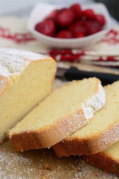 slices of pound cake sitting on top of a counter next to a bowl of strawberries