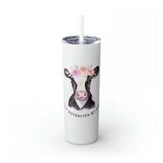 a white tumbler with a black and white cow wearing a flower crown on it's head