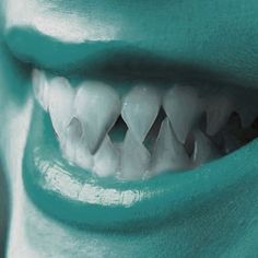 a close up of a person's teeth with white teeth and green paint on it