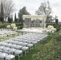 an outdoor ceremony setup with white chairs and flowers