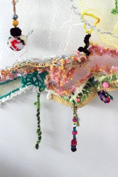 there is a piece of art made out of fabric and beads hanging from the ceiling