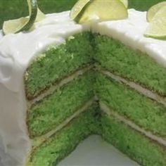 there is a green cake with white frosting and limes on the top slice