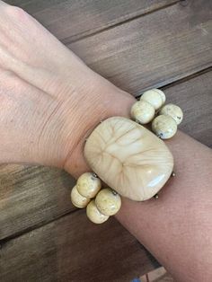 This exquisite double-stranded bracelet features a harmonious blend of fossil beads in a soft beige hue, elegantly arranged to highlight its rustic charm. At its center, a large, captivating focal piece in bronze and beige serves as a stunning centerpiece, adding a touch of elegance and sophistication. This bracelet effortlessly combines earthy tones with refined artistry, making it a versatile accessory for any occasion. Adjustable Cream Jewelry With Large Beads, Adjustable Beige Stretch Bracelet, Adjustable Beaded Bone Jewelry, Adjustable Bone Colored Beaded Jewelry, Hand-strung Beige Beaded Bracelets, Adjustable Bone-colored Bracelet, Adjustable Beige Large Beads, Rustic Bracelet, Soft Beige