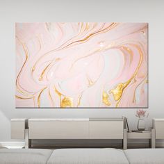 an abstract painting in pink and gold on a white wall above a couch with pillows