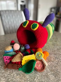 a crocheted caterpillar sits on top of other crochet toys