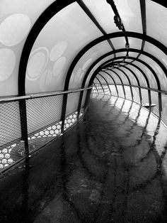 a black and white photo of a tunnel with lots of glass on the sides,