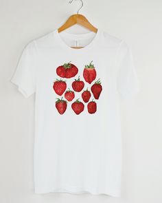 Is it strawberry season yet? These are freshly picked, just for you! T-shirt featuring a botanical illustration of sweet red strawberries, the design you won't find anywhere else. Printed on a crisp white t-shirt, made from durable lightweight cotton. Unisex fit - boxy and long. How it's made: * All prints are original watercolor designs hand-painted by a botanical artist. * Ethically made 100% cotton t-shirts that are made to last. * T-shirts are printed and shipped by my printing partner in the US, Canada, or Europe. * By buying from this shop you are directly supporting a woman-owned small business, created out of love for plants to educate, inspire and keep us connected to the natural world. About the artist: This Shop is an extension of my botanical illustration studio, where I create Red Fruit Print Graphic Tee, Red Graphic Tee With Fruit Print, Relaxed Fit Crew Neck Shirt With Strawberry Print, Strawberry Clothes, Watercolor Strawberry, Strawberry Gifts, Fruit Shirt, Strawberry Shirt, Strawberry Season