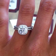 a woman's hand with a diamond ring on top of her finger and the other hand holding an engagement ring