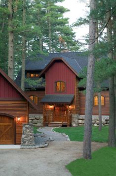 a red house in the woods surrounded by pine trees and rocks, with lights on